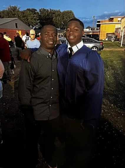 Two of the Seals sons together outdoors, dressed for a graduation.
