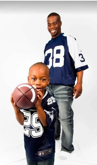 Chief Seals in a football jersey with his young son, who is holding a football.